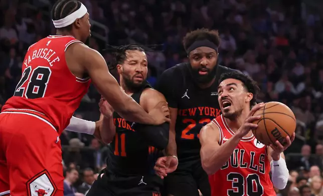 Chicago Bulls guard Tre Jones (30) drives to the basket past New York Knicks guard Jalen Brunson (11) and New York Knicks center Mitchell Robinson during the first half of an NBA basketball game, Friday, April 3, 2026, in New York. (AP Photo/Heather Khalifa)