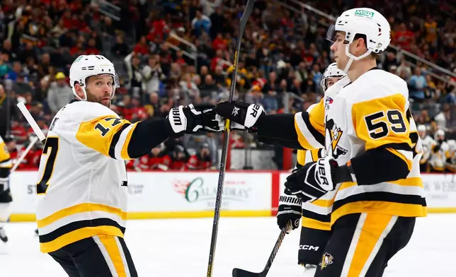 Pittsburgh Penguins right wings Bryan Rust (17) celebrates with Egor Chinakhov (59) after scoring a goal against the New Jersey Devils during the first period of an NHL hockey game, Thursday, April 9, 2026, in Newark, N.J. (AP Photo/Noah K. Murray)