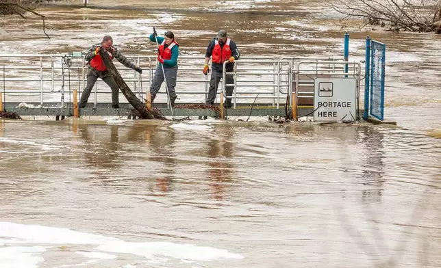 A team of assorted municipality workers clear debris from the Boardman River Weir that was blocking the flow of the flooded Boardman/Ottaway River on Wednesday, April 15, 2026, in downtown Traverse City, Mich. (Jan-Michael Stump/Traverse City Record-Eagle via AP)