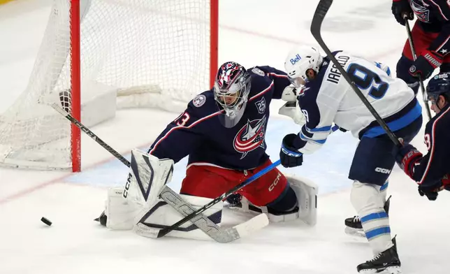 Columbus Blue Jackets goalie Jet Greaves, left, stops a shot in front of Winnipeg Jets forward Alex Iafallo during the third period of an NHL hockey game in Columbus, Ohio, Saturday, April 4, 2026. (AP Photo/Paul Vernon)