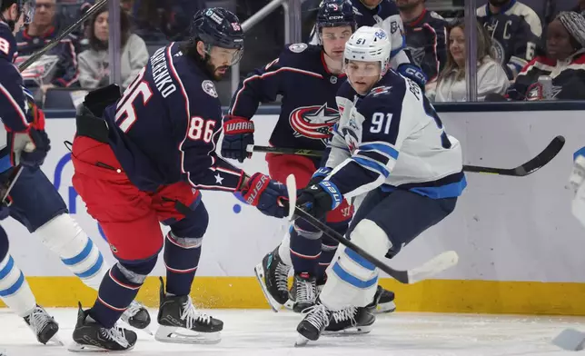 Columbus Blue Jackets forward Kirill Marchenko (86) reaches for the puck in front of Winnipeg Jets forward Cole Perfetti (91) during the second period of an NHL hockey game in Columbus, Ohio, Saturday, April 4, 2026. (AP Photo/Paul Vernon)