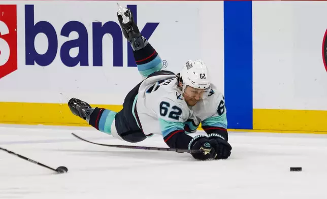 Seattle Kraken's Brandon Montour (62) dives for the puck during the third period of an NHL hockey game Tuesday, April 7, 2026, in St. Paul, Minn. (AP Photo/Lily Dozier)