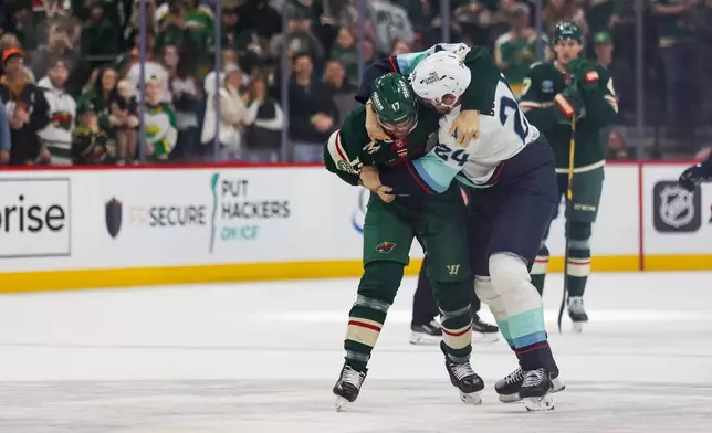 Minnesota Wild's Marcus Foligno (17) and Seattle Kraken's Jamie Oleksiak (24) fight during the first period of an NHL hockey game Tuesday, April 7, 2026, in St. Paul, Minn. (AP Photo/Lily Dozier)