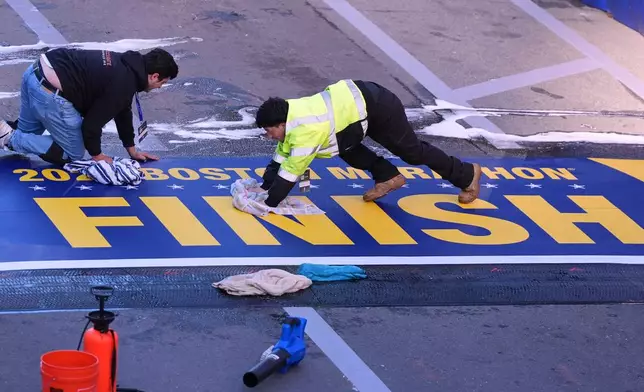 Workers scrub the finish line clean prior to the Boston Marathon, Monday, April 20, 2026, in Boston. (AP Photo/Charles Krupa)
