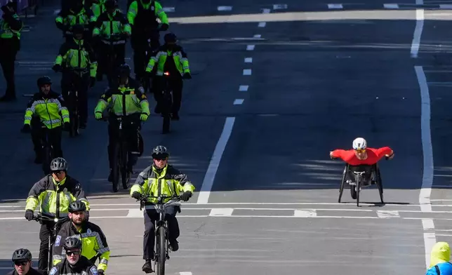 Jetze Plat, of the Netherlands, right, passes police cyclists while approaching the finish line of the Boston Marathon, Monday, April 20, 2026, in Boston. (AP Photo/Charles Krupa)