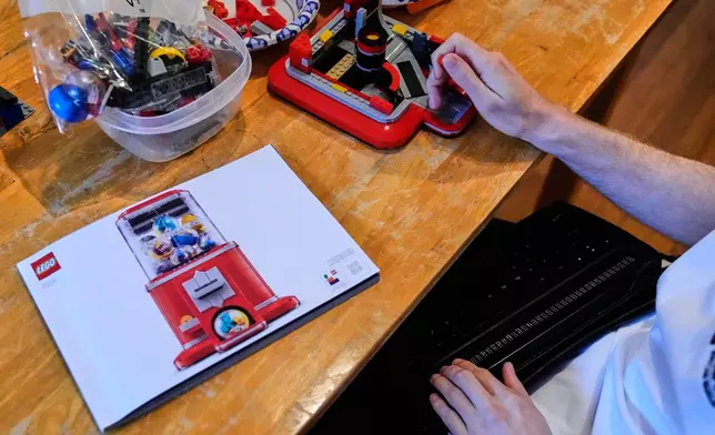 Matthew Shifrin, the founder of Bricks for the Blind, reads from a braille terminal while building a LEGO gum ball machine at his family's home, Friday, March 20, 2026, in Newton, Mass. (AP Photo/Charles Krupa)