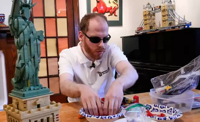 Matthew Shifrin, the founder of Bricks for the Blind, feels for specific pieces while building a LEGO gum ball machine at his family's home, Friday, March 20, 2026, in Newton, Mass. (AP Photo/Charles Krupa)