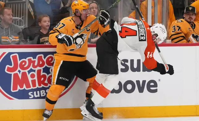 Pittsburgh Penguins' Sidney Crosby (87) checks Philadelphia Flyers' Sean Couturier, right, off his skates during the second period of Game 1 in the first round of the NHL Stanley Cup playoffs in Pittsburgh, Saturday, April 18, 2026. (AP Photo/Gene J. Puskar)