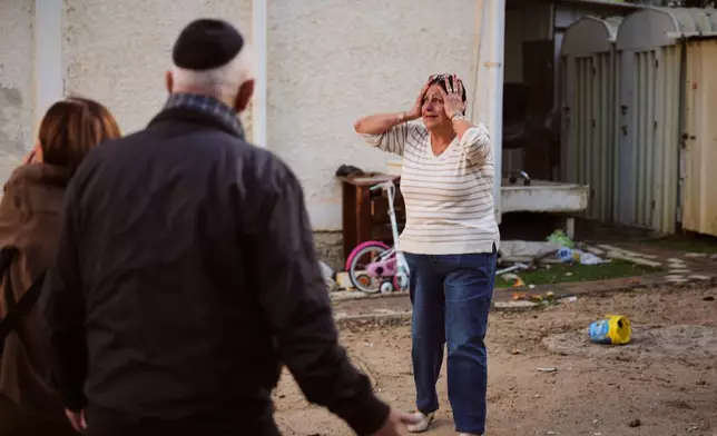 A woman reacts at the site of a damaged residential building after it was struck by a projectile fired from Lebanon, in Nahariya, northern Israel Monday, April 13, 2026. (AP Photo/Ariel Schalit)