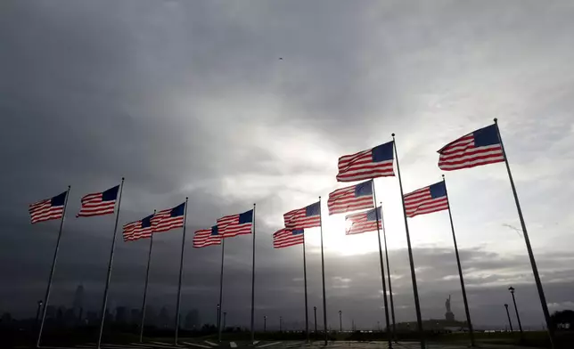 FILE - Thirteen United States flags representing the 13 original colonies are seen at Liberty State Park with 1 World Trade Center, bottom left, and the Statue of Liberty, bottom right, in the background, Sept. 11, 2014, in Jersey City, N.J. (AP Photo/Julio Cortez, File)