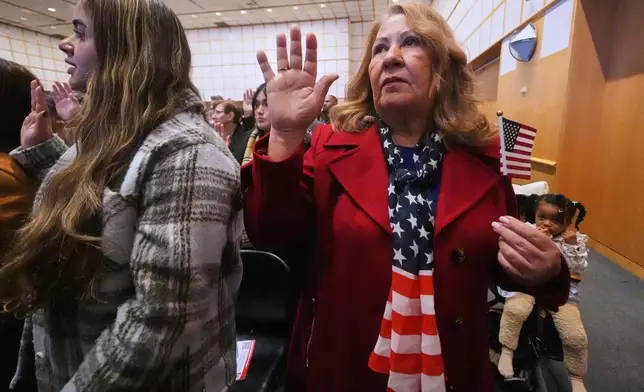 FILE - New citizen Ivette Lagos, originally from Brazil, wears a stars and stripes scarf while reciting the Oath of Allegiance during a naturalization ceremony where nearly 200 people from more than 50 different countries became United States citizens at the John F. Kennedy Presidential Library, Nov. 18, 2025, in Boston. (AP Photo/Charles Krupa, File)