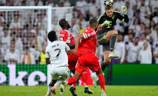 Bayern's goalkeeper Manuel Neuer heads the ball to save before Real Madrid's Vinicius Junior, left, can score during the Champions League quarterfinal first leg soccer match between Real Madrid and Bayern Munich in Madrid, Spain, Tuesday, April 7, 2026. (AP Photo/Jose Breton)