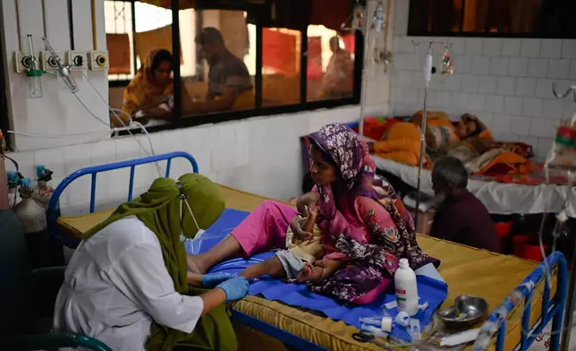 A nurse treats a child suffering from measles at the Infectious Diseases Hospital in Dhaka, Bangladesh, Monday, April 6, 2026, amid a countrywide outbreak. (AP Photo/Mahmud Hossain Opu)