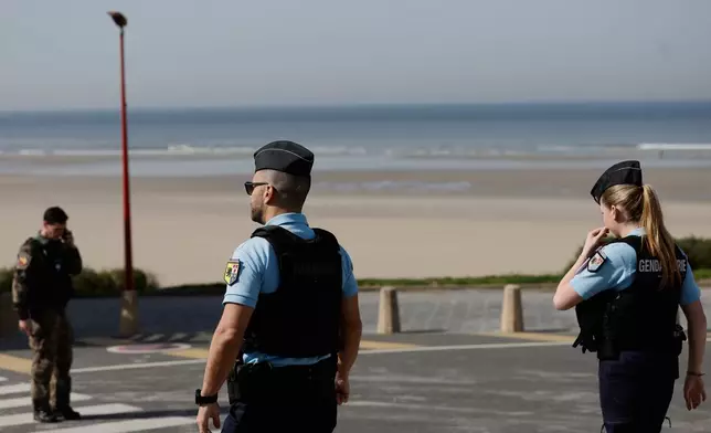 Policemen stand guard after a migrant taxi-boat accident, in Equihen-Plage, northern France, Thursday, April 9, 2026. (AP Photo/Jean-Francois Badias)