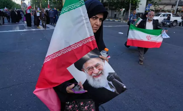 A woman carries an Iranian flag and a poster of the late Supreme Leader Ayatollah Ali Khamenei during a state-organised rally in Tehran, Iran, Wednesday, April 29, 2026, celebrating the birthday of Imam Reza, the 8th Shiite Muslims' Imam, and supporting Supreme Leader Ayatollah Mojtaba Khamenei. (AP Photo/Vahid Salemi)
