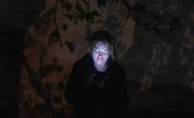 A woman speaks via a phone in front of her house damaged after a Russian strike on residential area in Kyiv, Ukraine, on Thursday, April 16, 2026. (AP Photo/Evgeniy Maloletka)