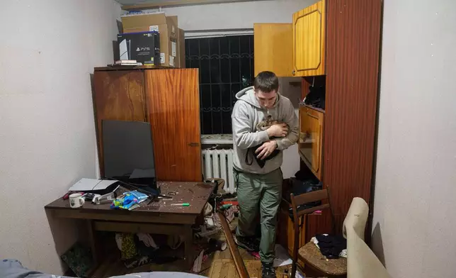 A man carries his bunny inside a house damaged after a Russian strike on residential area in Kyiv, Ukraine, on Thursday, April 16, 2026. (AP Photo/Evgeniy Maloletka)