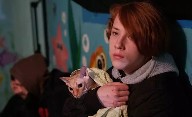 A boy holds his cat as he takes shelter inside a house damaged after a Russian strike on residential neighbourhood in Kyiv, Ukraine, on Thursday, April 16, 2026. (AP Photo/Evgeniy Maloletka)