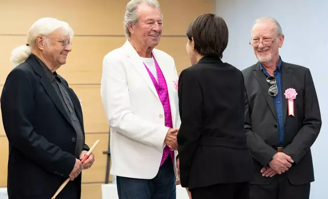 Japan's Prime Minister Sanae Takaichi, back to camera, greets members of British rock band Deep Purple , from left, Ian Paice, Ian Gillan, and Roger Glover at the Prime Minister's Office in Tokyo, Friday, April 10, 2026. (Yuichi Yamazaki/Pool Photo via AP)