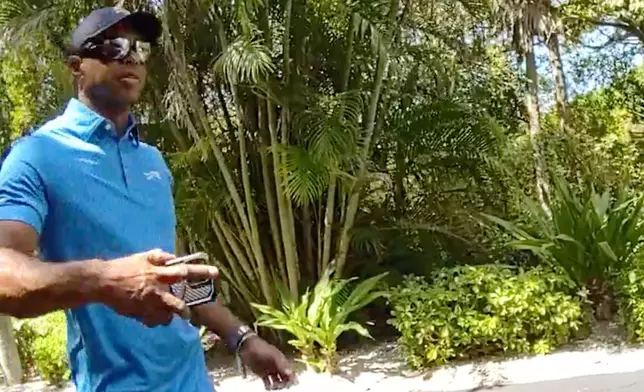 In this image from police body camera video released by the Martin County, Fla., Sheriff's Office, golfer Tiger Woods hangs up his cellphone and tells a sheriff deputy “I was just talking to the president" following a car crash in Jupiter Island, Fla., Friday, March 27, 2026. (Martin County Sheriff's Office via AP)