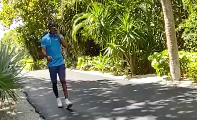 In this image from police body camera video released by the Martin County, Fla., Sheriff's Office, golfer Tiger Woods speaks on his cellphone following a car crash in Jupiter Island, Fla., Friday, March 27, 2026. (Martin County Sheriff's Office via AP)