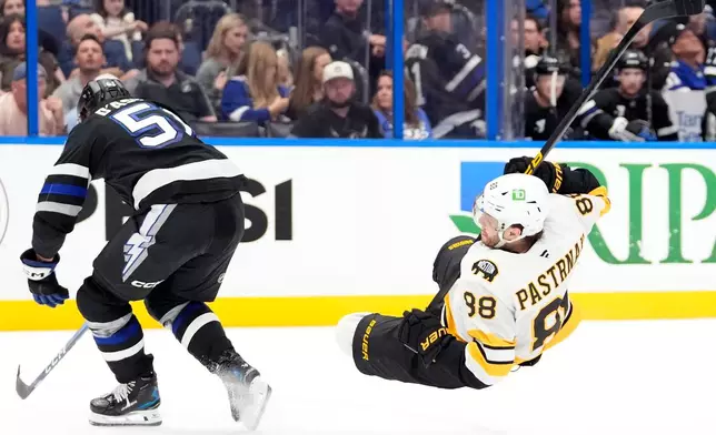 Tampa Bay Lightning defenseman Charle-Edouard D'Astous (51) knocks down Boston Bruins right wing David Pastrnak (88) during the third period of an NHL hockey game Saturday, April 4, 2026, in Tampa, Fla. (AP Photo/Chris O'Meara)