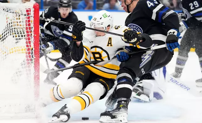 Tampa Bay Lightning defenseman Darren Raddysh (43) takes down Boston Bruins defenseman Charlie McAvoy (73) during the first period of an NHL hockey game Saturday, April 4, 2026, in Tampa, Fla. (AP Photo/Chris O'Meara)