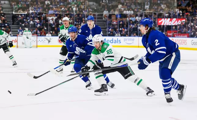 Dallas Stars center Mavrik Bourque (22) reaches for a puck against Toronto Maple Leafs defenceman Simon Benoit (2) during the first period of an NHL hockey game, in Toronto, Monday, April 13, 2026. (Cole Burston/The Canadian Press via AP)
