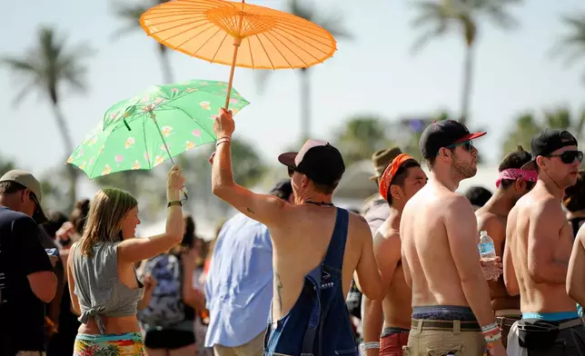 FILE - Festivalgoers shield themselves from the sun at the Coachella Music and Arts Festival in Indio, Calif., on April 13, 2014. (Photo by Chris Pizzello/Invision/AP, File)