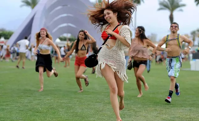 FILE - Festivalgoers run toward the main stage at the Coachella Valley Music and Arts Festival in Indio, Calif., on April 13, 2012. (AP Photo/Chris Pizzello, File)