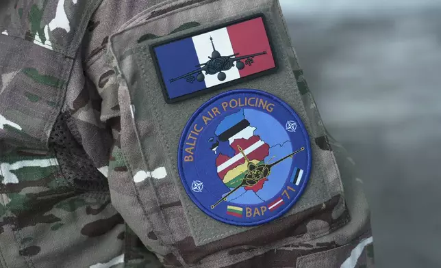 A member of the French air wing of Rafale fighters jets deployed on a NATO air-policing mission at the Siauliai Air Base in Lithuania wears a mission badge on her arm on Sunday, April 19, 2026 (AP Photo/John Leicester).