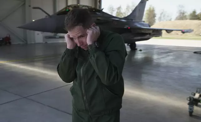 French air force Commander Dorian (surname withheld by the French military) uses his hands to shield his ears from the scream of the jet engines of a Rafale fighter preparing to take off from the Siauliai Air Base in Lithuania on a NATO air-policing mission on Monday, April 20, 2026. (AP Photo/John Leicester)