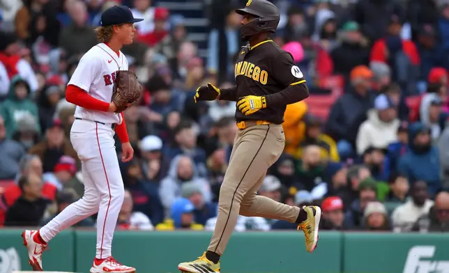 San Diego Padres' Miguel Andujar, right, runs toward home past Boston Red Sox pitcher Connelly Early, left, to score on a one-run double by Freddy Fermin in the third inning of a baseball game, Saturday, April 4, 2026, in Boston. (AP Photo/Steven Senne)