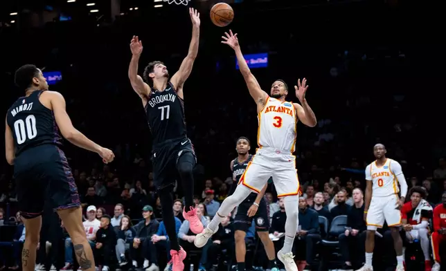 Atlanta Hawks guard CJ McCollum (3), defended by Brooklyn Nets guard Ben Saraf (77), shoots a two-pointer during the first half of an NBA basketball game, Friday, April 3, 2026, in New York. (AP Photo/Angelina Katsanis)