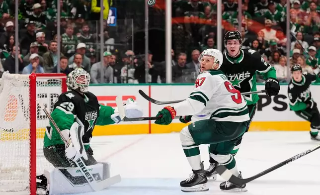 Dallas Stars goaltender Jake Oettinger (29) keeps his eyes on an airborne puck as Minnesota Wild's Kirill Kaprizov (97) pressures the net in the second period of Game 2 of a first-round NHL Stanley Cup playoffs hockey series Monday, April 20, 2026, in Dallas. (AP Photo/Tony Gutierrez)un