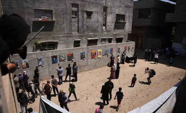 People look at paintings by Palestinian artists during an exhibition in Al-Bureij camp in the central Gaza Strip Tuesday, April 28, 2026. (AP Photo/Abdel Kareem Hana)