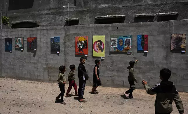 Children look at paintings by Palestinian artists during an exhibition in Al-Bureij camp in the central Gaza Strip Tuesday, April 28, 2026. (AP Photo/Abdel Kareem Hana)