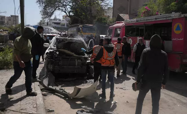 Palestinian civil defense crews work on a destroyed car after it was struck in an Israeli strike in Gaza City Tuesday, April 28, 2026. (AP Photo/Jehad Alshrafi)