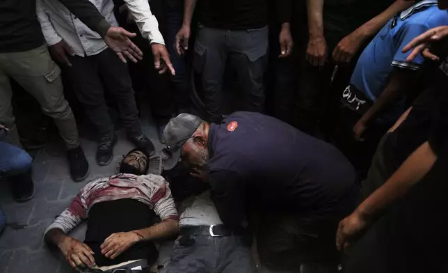 EDS NOTE: GRAPHIC CONTENT - Palestinians gather around the bodies of Iyad, Al-Shambari and his son Salah, who were killed in an Israeli airstrike, at Al-Shifa Hospital in Gaza City , Tuesday, April 28, 2026 (AP Photo/Jehad Alshrafi)
