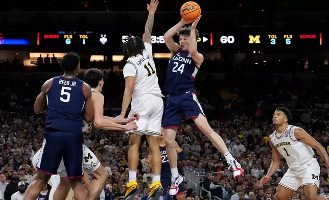 UConn guard Braylon Mullins (24) dishes off around Michigan guard Roddy Gayle Jr. (11) during the second half of the NCAA college basketball tournament national championship game at the Final Four, Monday, April 6, 2026, in Indianapolis. (AP Photo/Abbie Parr)