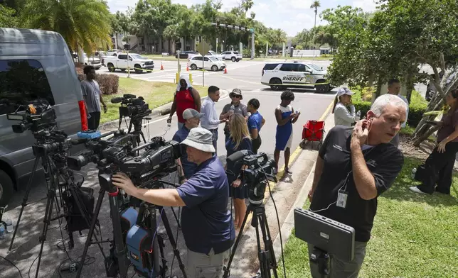 Members of the media document detectives and deputies with the Hillsborough County Sheriff's Office as they investigate inside the Lake Forest subdivision of Tampa, Fla., on Friday, April 24, 2026, where authorities said a man was taken into custody after barricading himself inside a home, in connection to the search for two missing University of South Florida graduate students. (Douglas R. Clifford/Tampa Bay Times via AP)