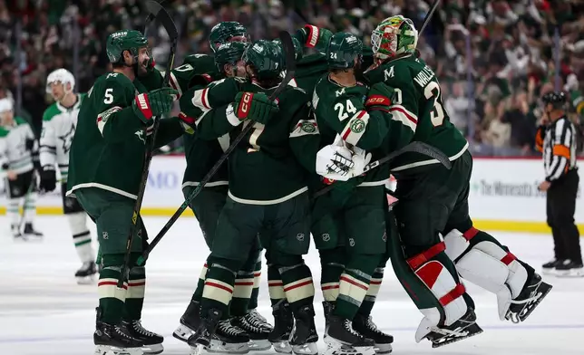 Minnesota Wild players celebrate after their team's win over the Dallas Stars during overtime of Game 4 in the first round of the NHL Stanley Cup hockey playoffs Saturday, April 25, 2026, in St. Paul, Minn. (AP Photo/Matt Krohn)
