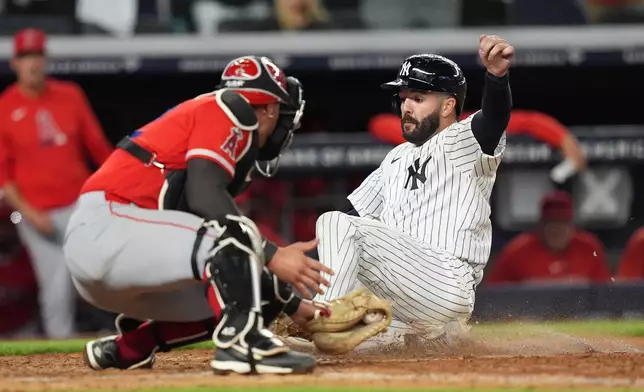 New York Yankees' Austin Wells slides past Los Angeles Angels catcher Logan O'Hoppe to score on a double by José Caballero during the ninth inning of a baseball game Wednesday, April 15, 2026, in New York. (AP Photo/Frank Franklin II)