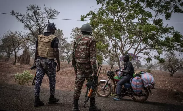 FILE - A police officer and a soldier from Benin stop a motorcyclist at a checkpoint, outside Porga, Benin, March 26, 2022. (AP Photo/ Marco Simoncelli, File)