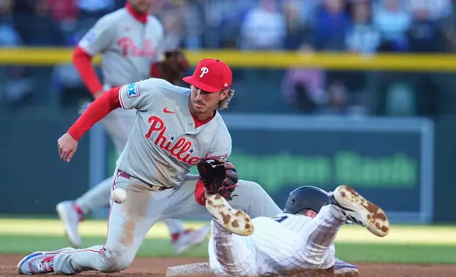 Philadelphia Phillies second baseman Bryson Stott, left, fields a throw to tag out Colorado Rockies' Brenton Doyle, right, who tries to steal second in the first inning of a baseball game Saturday, April 4, 2026, in Denver. (AP Photo/David Zalubowski)