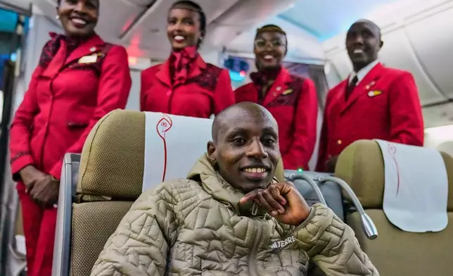 Sabastian Sawe poses with air hostesses aboard a plane from London, Wednesday, April 29, 2026, upon arrival at Jomo Kenyatta International Airport in Nairobi, Kenya, after setting a new world record in the marathon. (AP Photo/Brian Inganga) CORRECTION: Corrects spelling of first name to Sabastian, not Sebastian