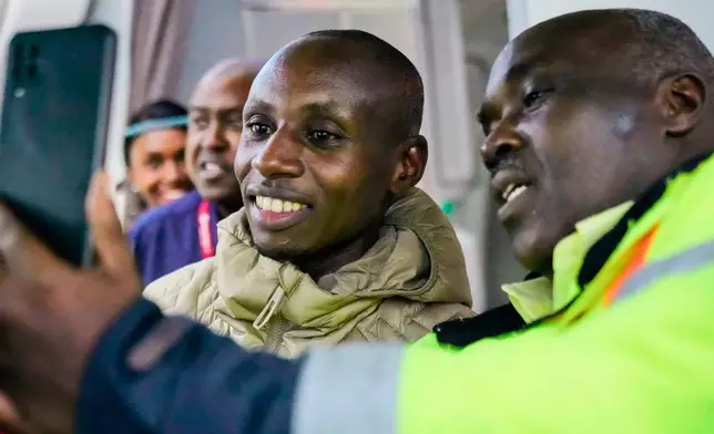 Sabastian Sawe poses for a selfie with an airport worker after arriving on a plane from London, Wednesday, April 29, 2026, at Jomo Kenyatta International Airport in Nairobi, Kenya, after setting a new world record in the marathon. (AP Photo/Brian Inganga) CORRECTION: Corrects spelling of first name to Sabastian, not Sebastian