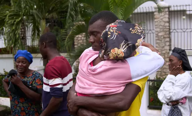 Relatives of a victim of a deadly stampede embrace each other in Milot, Haiti, Sunday, April 12, 2026. (AP Photo/Ketlain Difficile)