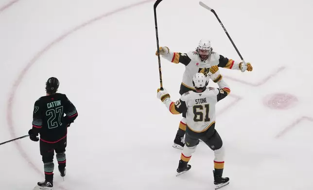 Vegas Golden Knights right wing Mark Stone (61) celebrates his goal with defenseman Rasmus Andersson (4) as Seattle Kraken center Berkly Catton (27) looks on during the first period of an NHL hockey game Thursday, April 9, 2026, in Seattle. (AP Photo/Lindsey Wasson)