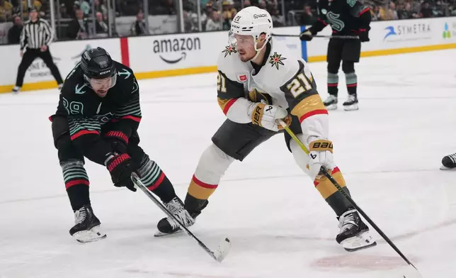 Vegas Golden Knights center Brett Howden (21) moves the puck against Seattle Kraken center Frederick Gaudreau, left, during the second period of an NHL hockey game Thursday, April 9, 2026, in Seattle. (AP Photo/Lindsey Wasson)